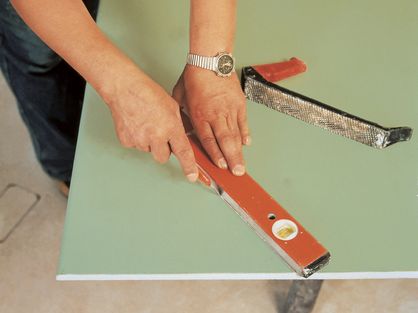 Platte auf der Sichtseite mit Universalmesser (Cuttermesser) mit Hilfe einer Latte oder Metallschiene anschneiden